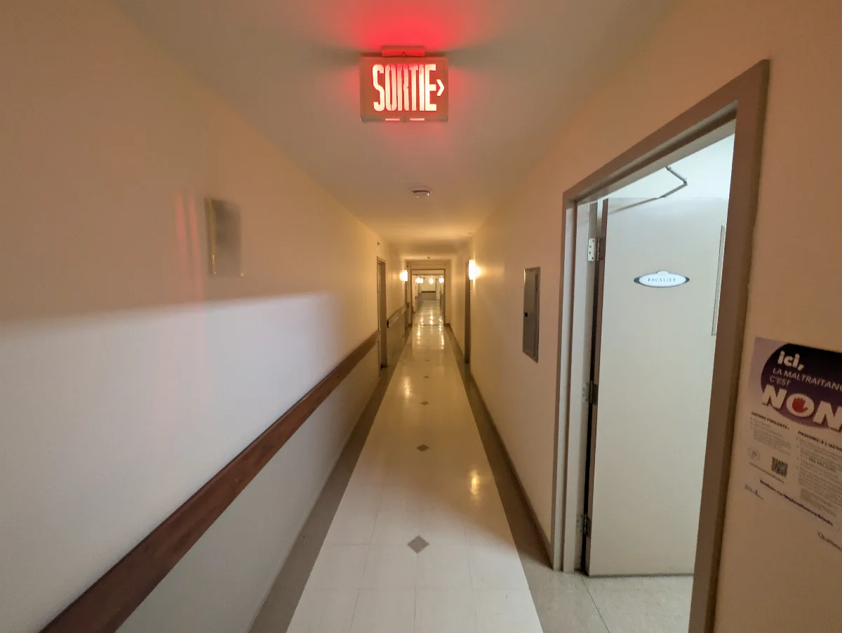 Corridor de la résidence avec barres d’appui et signalisation de sortie